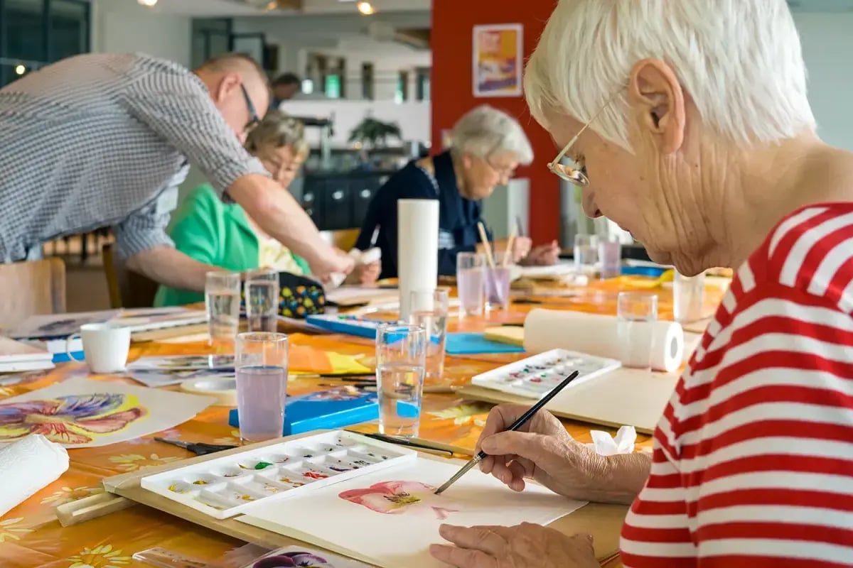 Residents painting together around a table during a group activity session