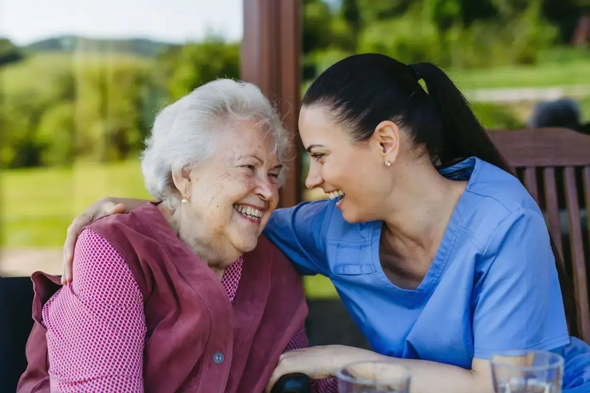 A carer and a resident laughing together outdoors