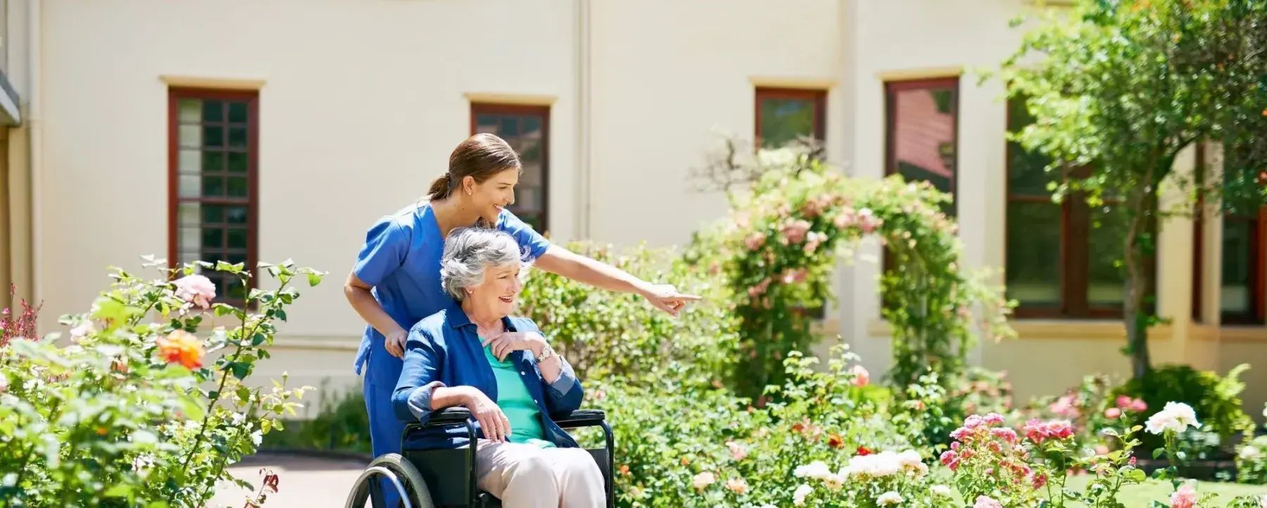 A carer walking with a resident through a care home garden