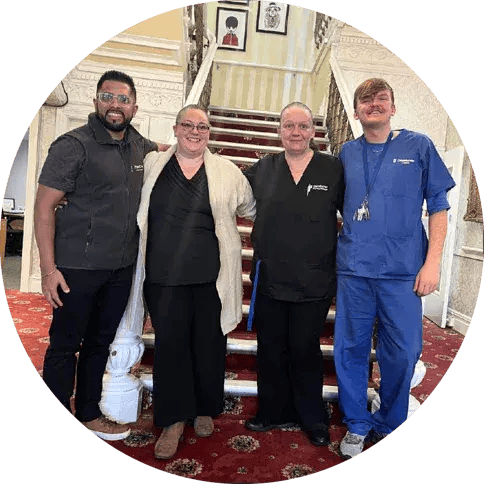 Four members of the Dovehaven team standing together on the staircase of one of their care homes