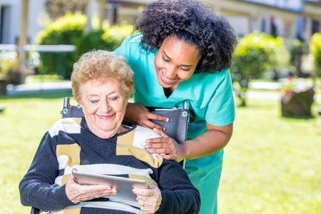carer-looking-at-tablet-held-by-woman-in-wheelchair