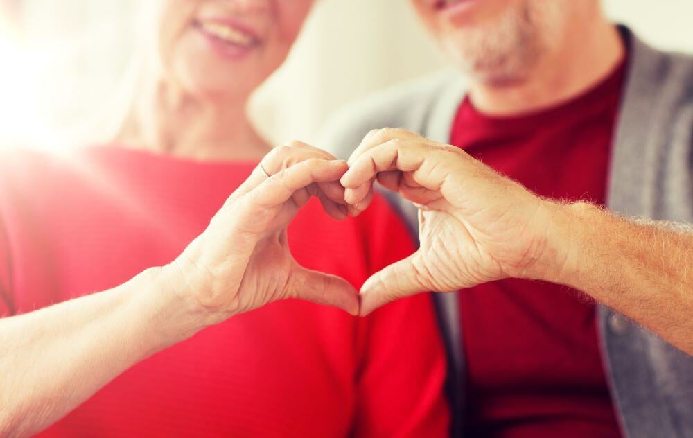 Two people wearing red T-shirts make a heart shape with their hands