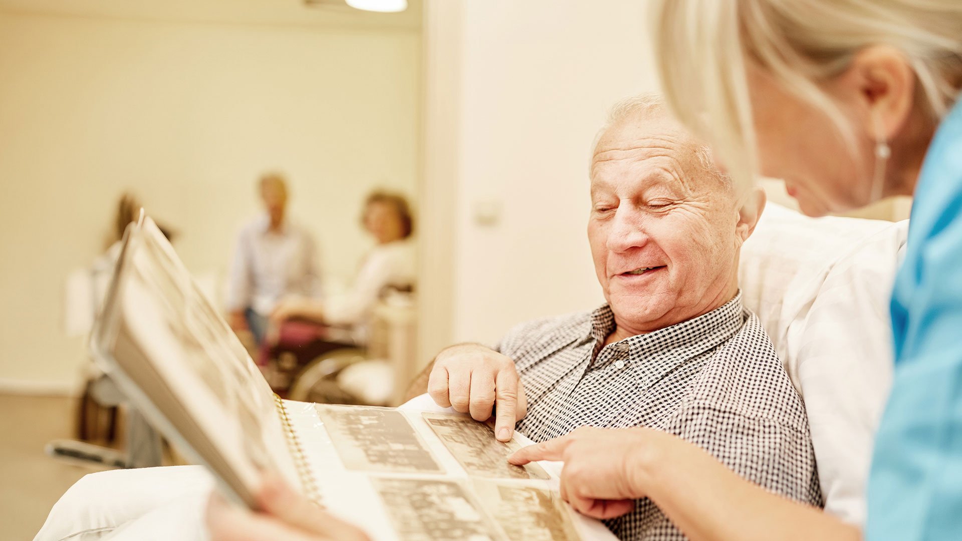 Resident man looks at a photo album with a carer