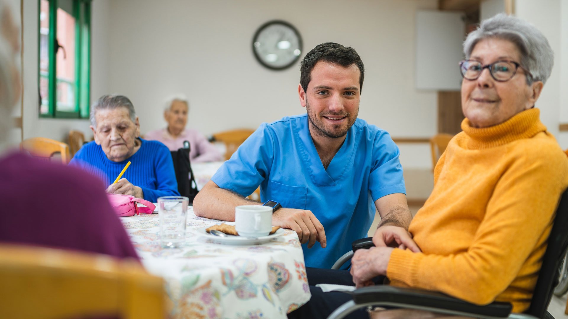 Resident woman in wheelchair at a table with a carer