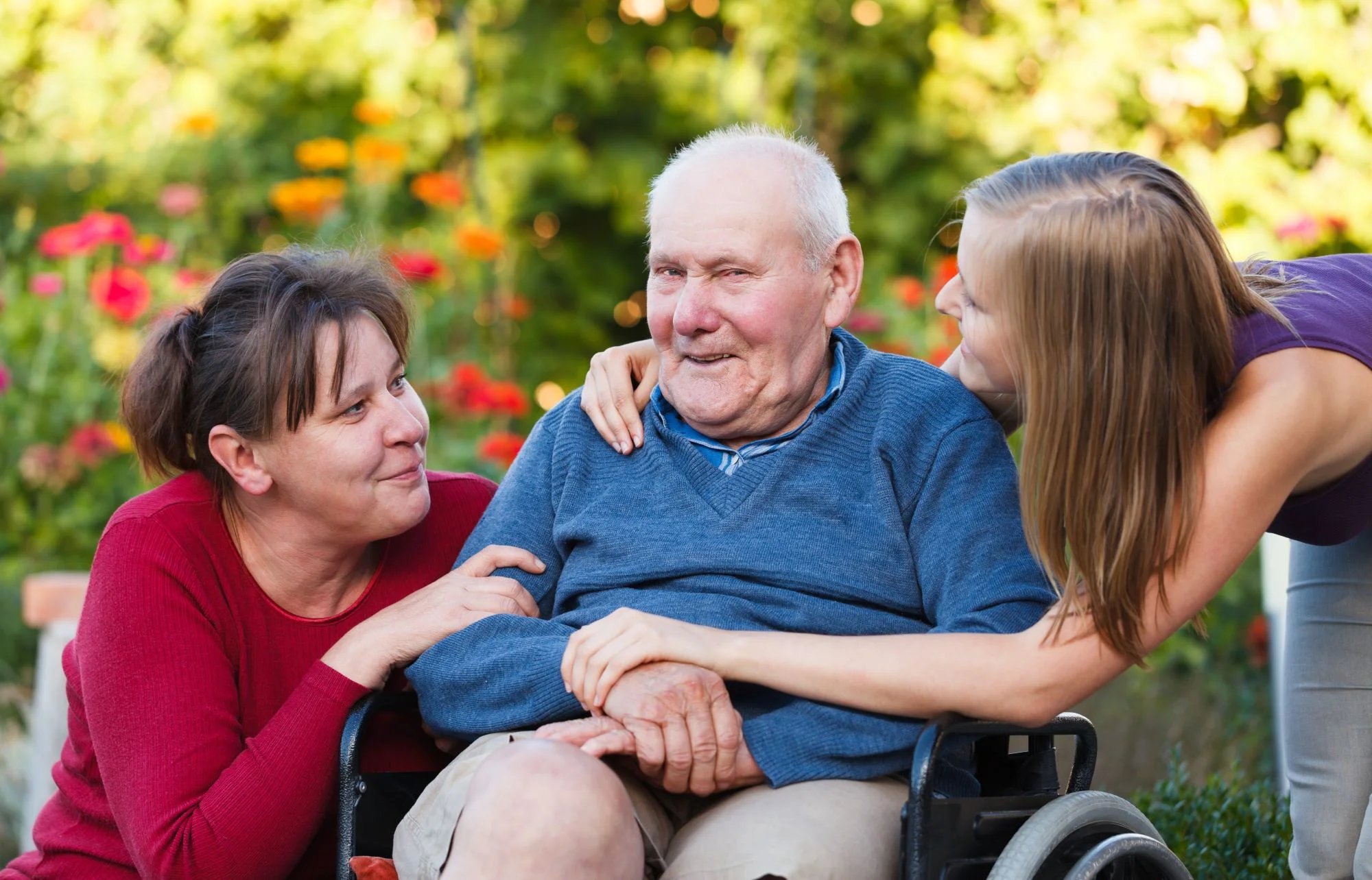 Resident man outside in wheelchair with two women