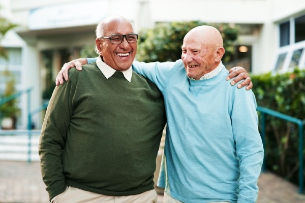 Two older men smiling with arms around shoulders