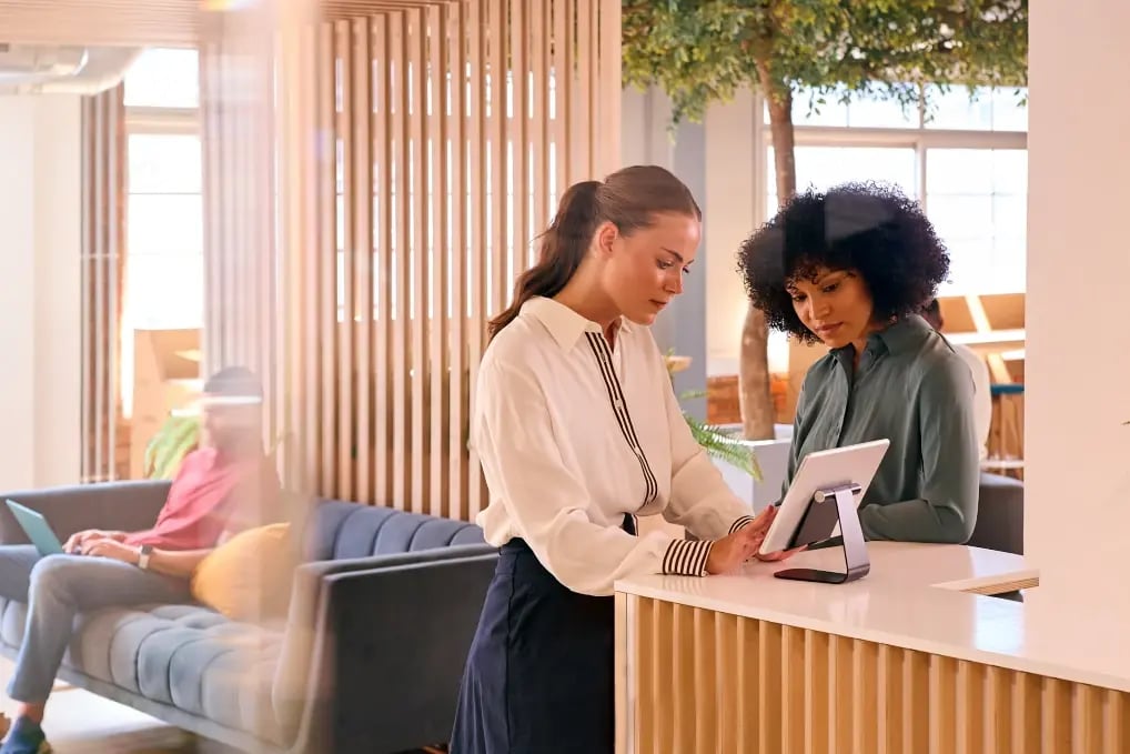 Woman uses a digital screen to check in at reception desk