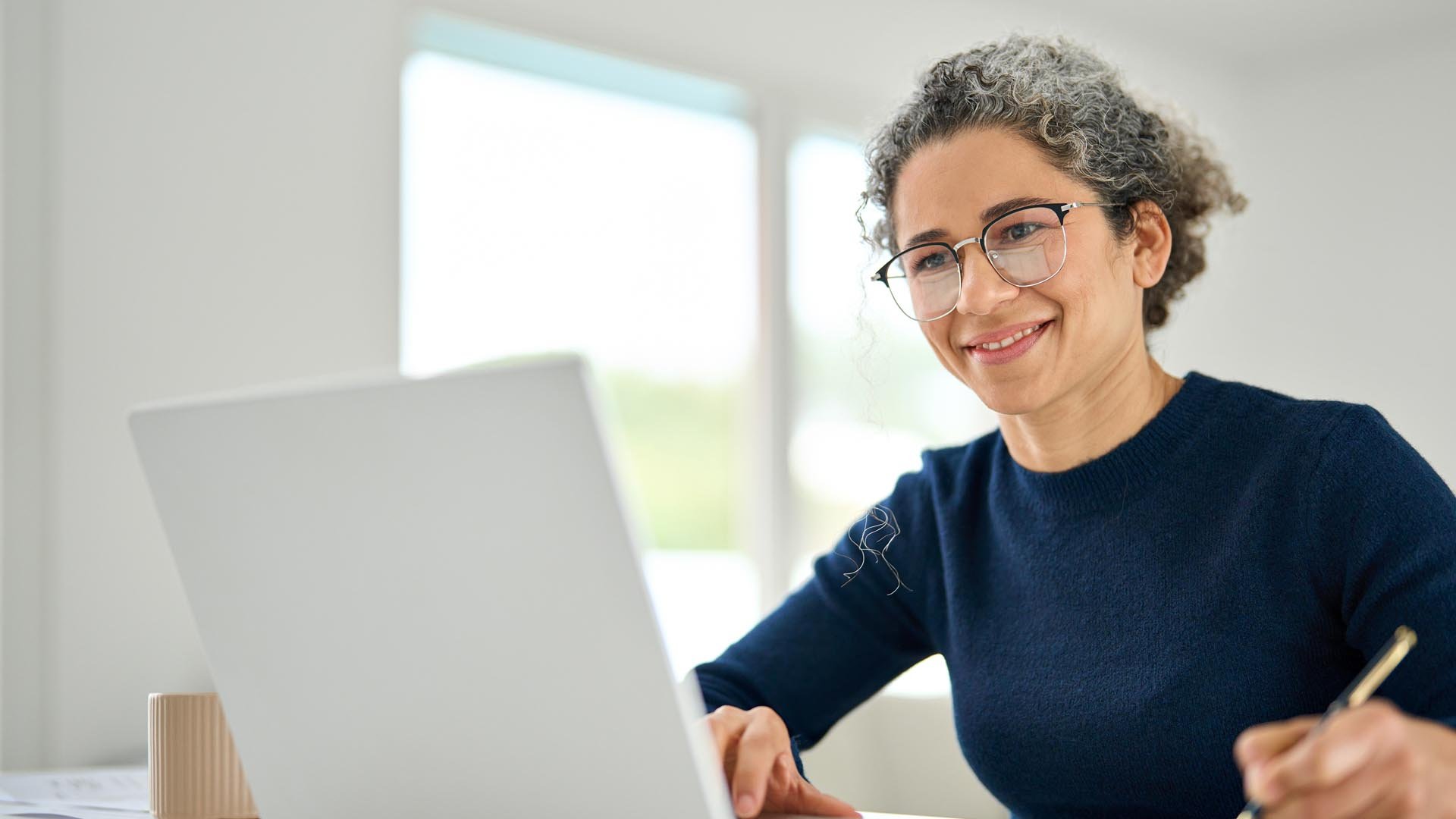 Woman studying with laptop using notepad and pen
