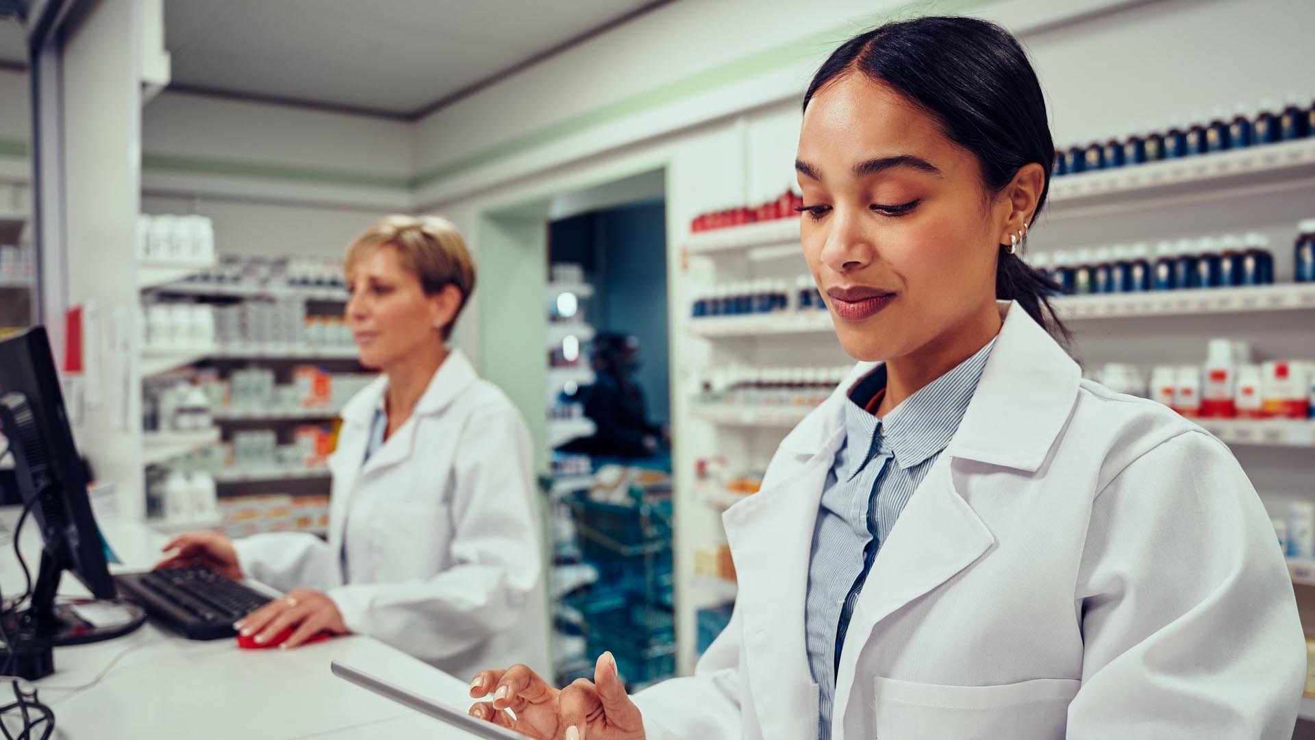 Two women work behind counter in a pharmacy
