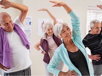 Residents taking part in a seated and standing group exercise session.
