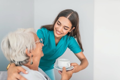 A care team member sharing a cup of tea with a resident.