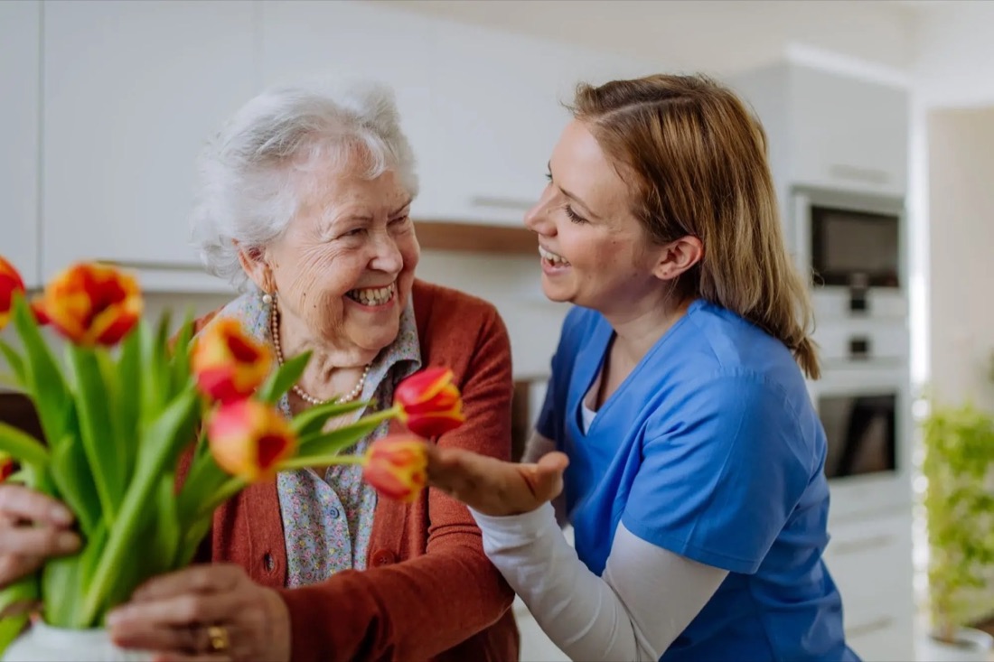 A resident laughing with a member of the care team while arranging flowers.